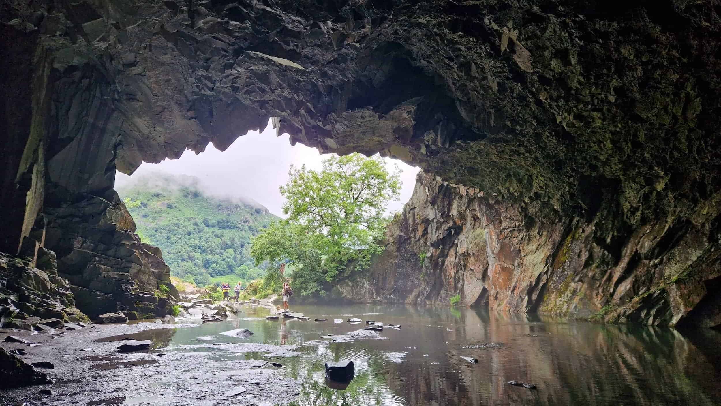 A cave interior featuring still water surrounded by rugged rocks, creating a serene and natural atmosphere.